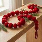 Guirnalda de bambalinas Mix roja sobre consola de madera con follaje navideño y candelabro.