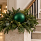 Bambalina mate verde de 25 cm en un arreglo navideño con follaje sobre pedestal
