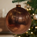 Bambalina Plisada bronce colgada de una rama de árbol de Navidad con luces cálidas