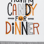 Zoom detalle bordado Having Candy for Dinner naranja negro flecos grises pompones negros paño cocina Halloween